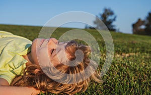 Happy child playing on green grass. Kids dreaming. Funny kid outdoor in spring garden. Children day. Happy carefree