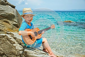 Happy child playing guitar by the sea greece on nature background