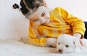 Happy child playing at home with little dogs. Pretty little girl with the puppy. Adorable kid hugging, playing with her pet at the