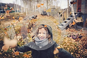 Happy child playing with leaves in autumn. Seasonal outdoor activities with kids