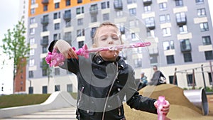 Happy child playing outdoors with soap bubbles on playground in early autumn. Action. Concept of childhood and leasure