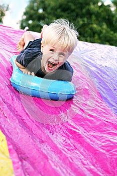 Happy Child Playing Outside on Backyard SLip-n-Slide