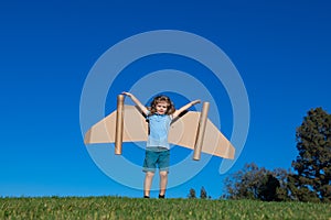 Happy child playing in park. Kid having fun with toy paper wings.