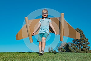 Happy child playing in park. Kid having fun with toy paper wings.