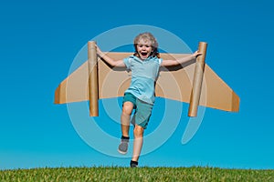 Happy child playing in park. Kid having fun with toy paper wings. Little boy in dreaming of becoming a pilot. Funny kid