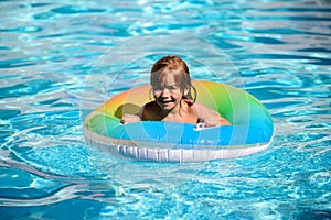 Happy child playing with swim float ring in swimming pool. Summer vacation. Healthy kids lifestyle.