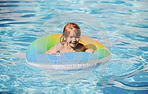 Happy child playing with swim float ring in swimming pool. Summer vacation. Healthy kids lifestyle.