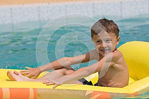 Happy child playing on the swimming pool at the day time.