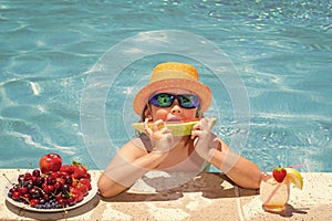 Happy child playing in swimming pool. Summer kids vacation. Summer fruit for children. Little kid boy relaxing in a pool