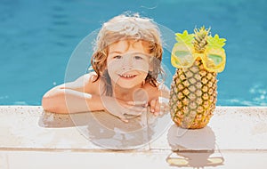 Happy child playing in swimming pool. Summer kids vacation. Summer pineapple fruit.