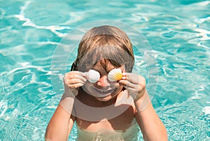 Happy child playing in swimming pool. Summer vacation concept. Covered eyes with shells.