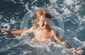 Happy child playing in swimming pool. Summer vacation concept. Hot tub. Summer kids holidays.