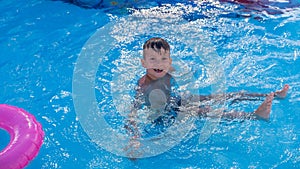 Happy child playing in water pool. cute wet