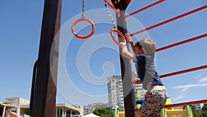 A happy child plays on a children`s Playground with rings on a Sunny summer day. Children`s outdoor games.