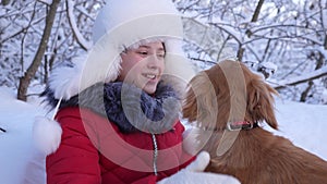 Happy child plays with dog in winter in the park for christmas vacation. girl with a hunting dog outdoors. The mistress