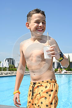 Happy child in the pool,drinking a summer refreshing drink