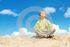 Happy Child Positive Think, Boy Sitting in Yoga Lotus position over blue sky on the top. Kid Happiness concept.