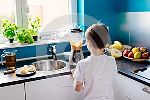 Happy child preparing fruit cocktail in kitchen