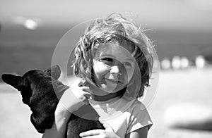 Happy child and puppy dog hugs her with tenderness smiling.