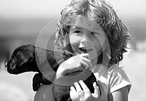 Happy child with puppy dog. Portrait kids boy with pet playing outside. Carefree childhood.