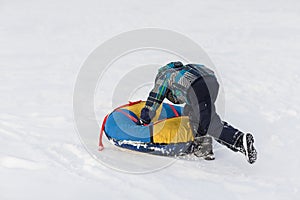 Happy child pushes the tubing in the snow in the winter frosty day