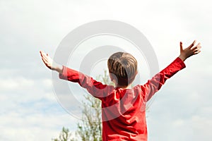 Happy child raising hands up at nature. Health, freedom and future concept. Happy childhood. Fresh air, environment. Dream of