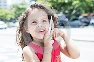 Happy child in a red shirt talking at phone