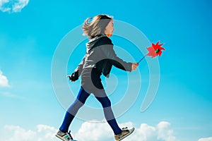 Happy child with red wind spinner on sky background.
