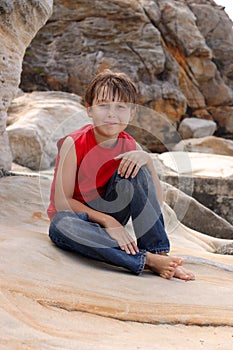 Happy child relaxes on rocks