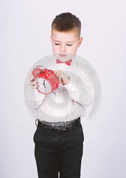 Happy child with retro clock in bow tie. little boy with alarm clock. Time to relax. Party time. Businessman. Formal