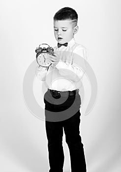 Happy child with retro clock in bow tie. Party time. Businessman. Formal wear. Time management. Morning. little boy with