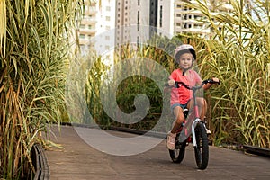 Happy child rides a bike on bike path. Cyclist child girl enjoys good weather and cycling