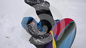 A happy child rides and falling in snowtube on a snowy hill