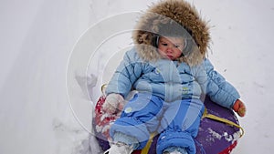 A happy child rides in snowtube on a snowy hill