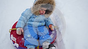 A happy child rides in snowtube on a snowy hill