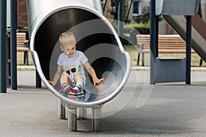 Happy child riding down slide on playground