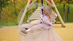 Happy child is riding a swing. Look into the camera and laugh. The girl flies on bungee. Cheerful childhood. Walk in