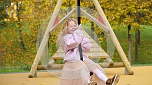 Happy child is riding a swing. Look into the camera and laugh. The girl flies on bungee. Cheerful childhood. Walk in