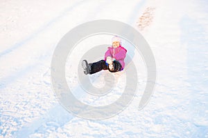 Happy child rolls down from the snow slide. Winter fun.