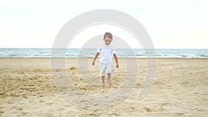 Happy child running along a sandy beach in slow motion