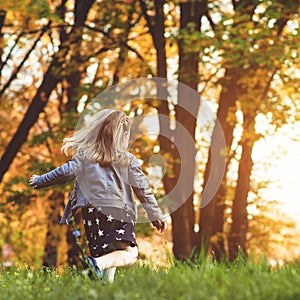 Happy child running at autumn park. Little girl playing outdoors. Beautiful golden autumn time. Happy and healthy childhood. Autum