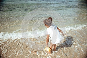 Adorable little girl splashing in tropical shallow water during summer vacation