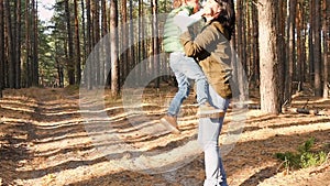 Happy child running on the road in the forest and laughing. The boy runs against the background of the forest towards