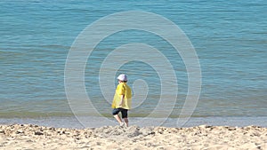 Happy child running on seashore, kid playing with sea waves