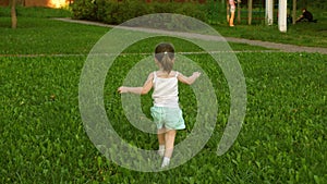 Happy child runs on a meadow in summer on a green grass. cheerful little girl runs across field. concept of happiness