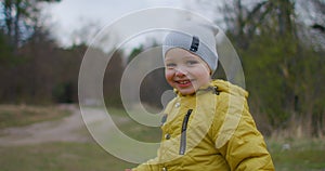Happy child runs to the camera in the park outdoors slow motion. Little boy running along the forest. Happy laughing boy