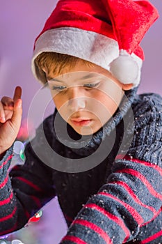 a happy child in Santa Claus\'s hat thinks about a gift and plaing