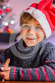 a happy child in Santa Claus\'s hat thinks about a gift and plaing