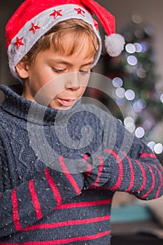 a happy child in Santa Claus\'s hat thinks about a gift and plaing