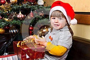 Happy child in Santa hat opening Christmas gift box